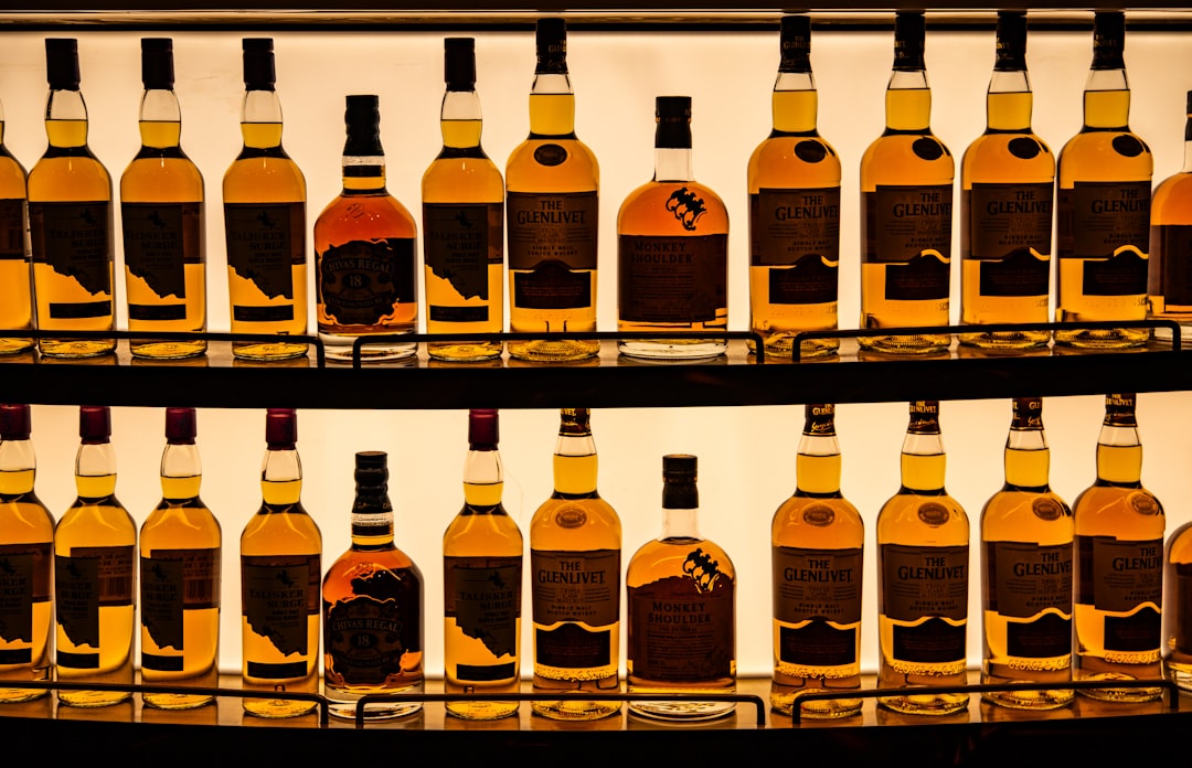 single malt whisky bottles lineup flat lay, golden amber whisky glass light